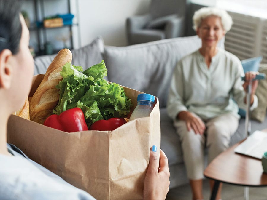 employee helping senior woman with groceries