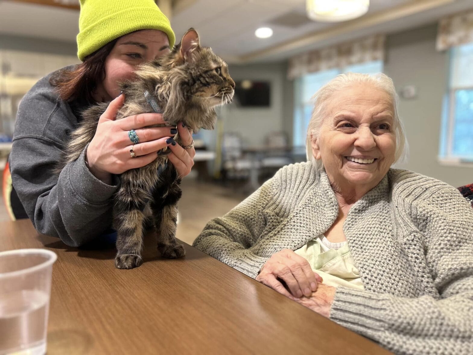 Smiling resident with cat on a table looking at her