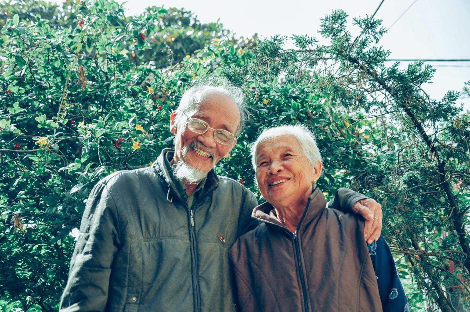 An elderly couple smiling and laughing with their arms around each other