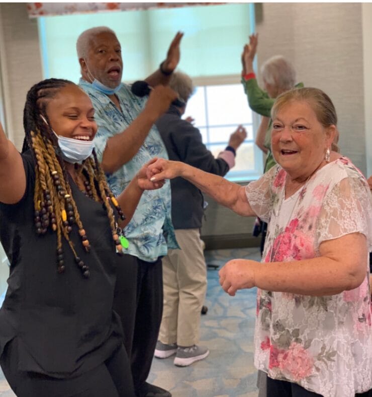 Assisted living residents dancing and smiling with care staff