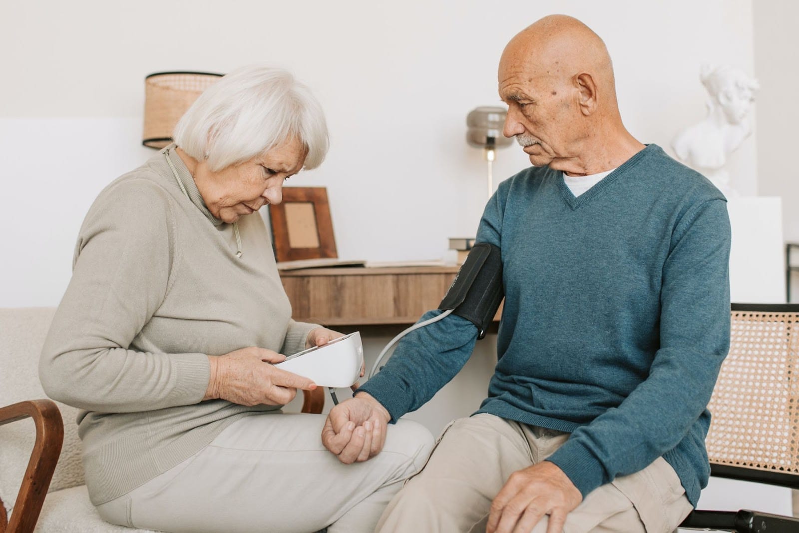 A woman taking the blood pressure of an elderly man