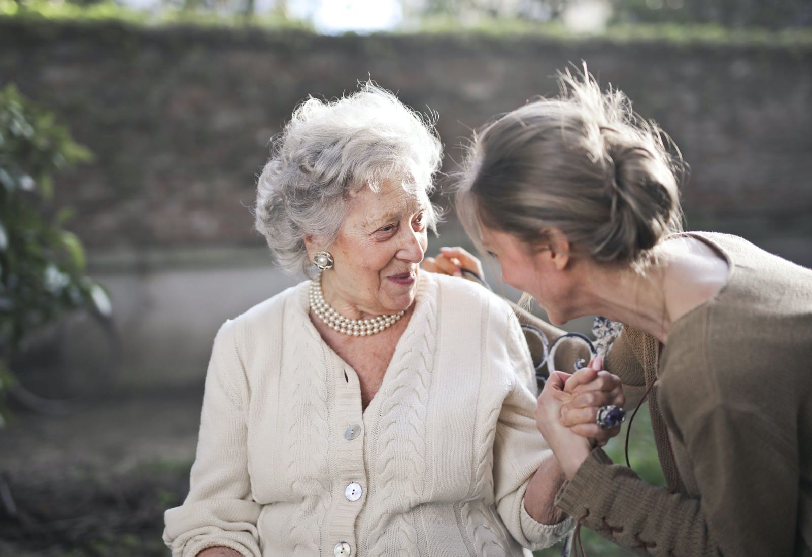 An elderly woman smiling and laughing with a younger woman
