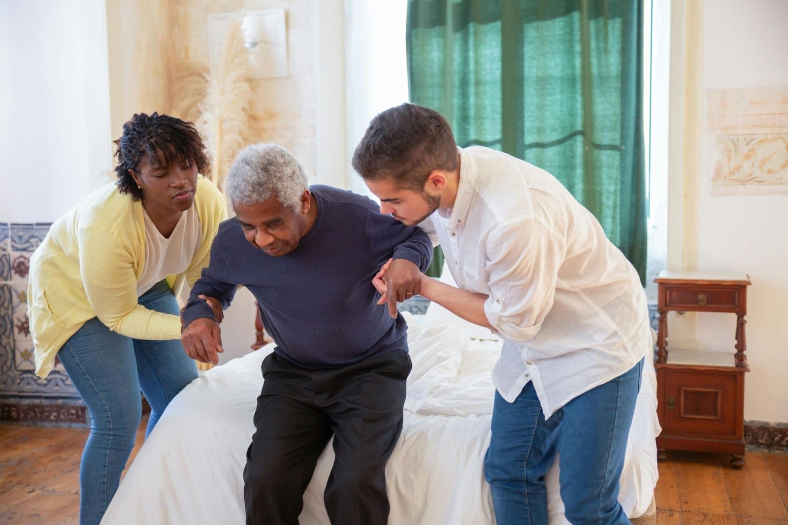 Respite care workers helping an elderly gentleman stand up from his bed