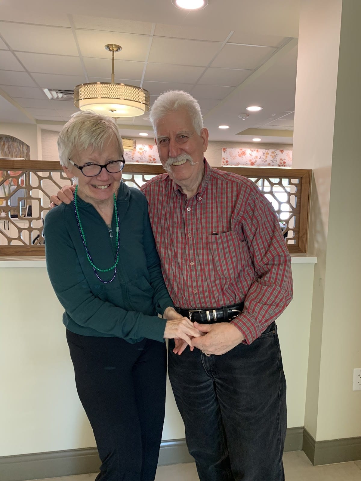 A couple standing in an assisted living facility and smiling