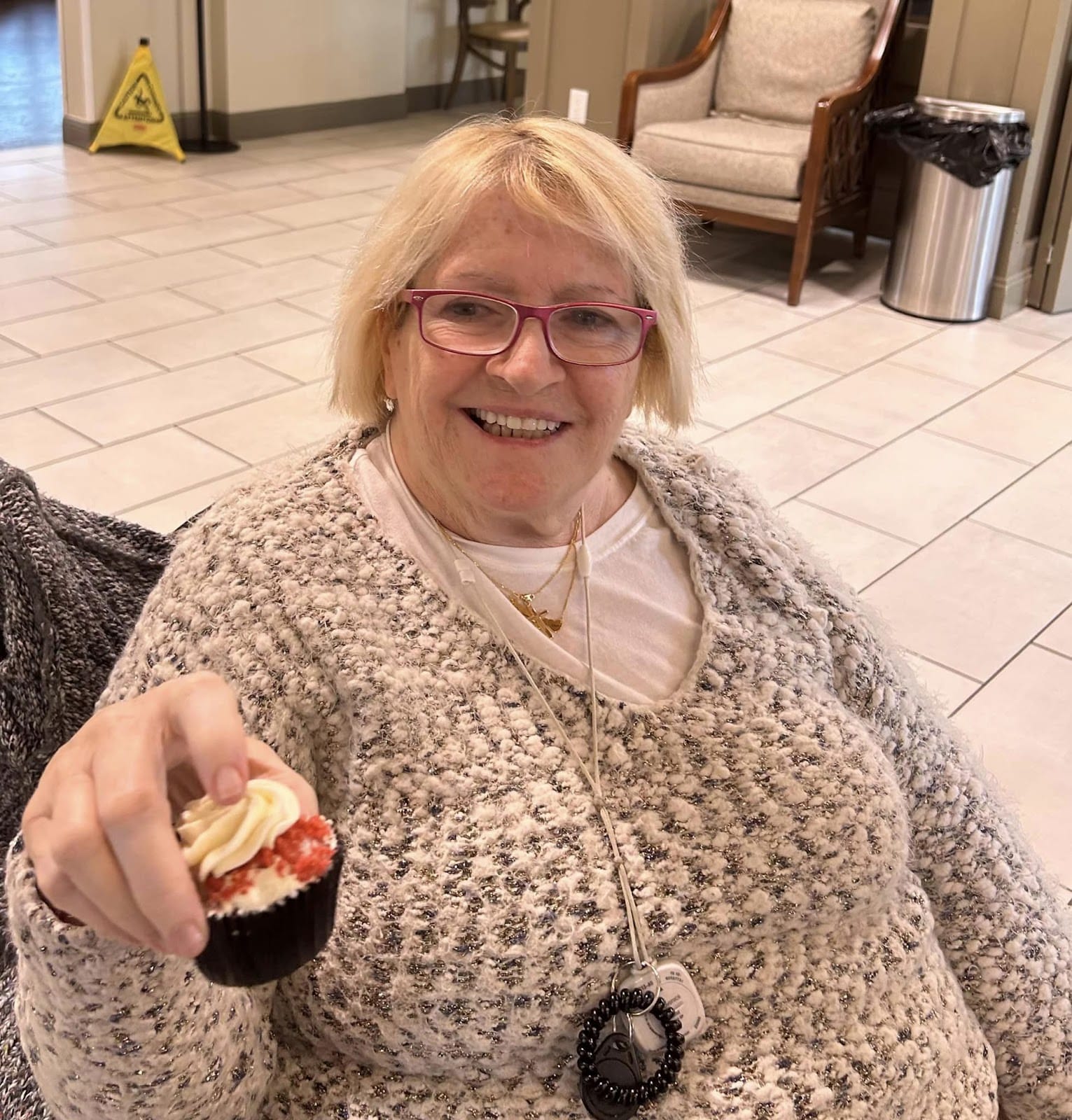 An elderly senior holding a cupcake and smiling