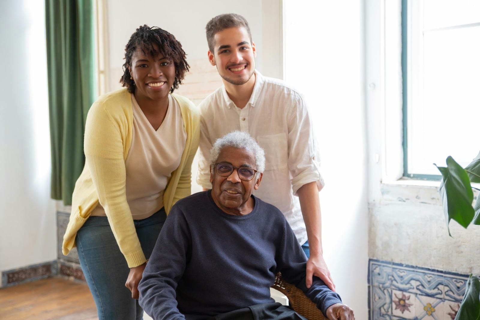Respite workers smiling with a senior  citizen in a chair in front of them