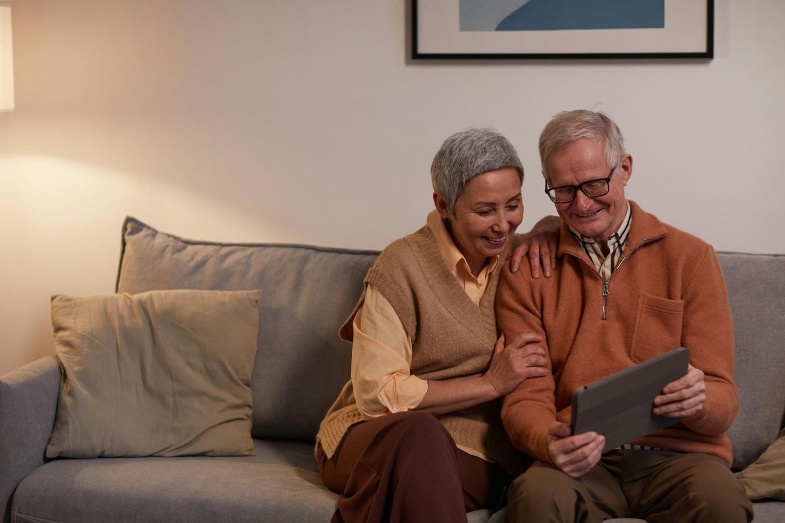 A senior citizen couple smiling while holding a digital tablet