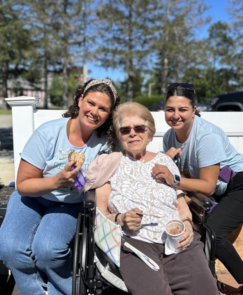 People from Village Green dementia care facility smiling and holding cookies with a senior citizen