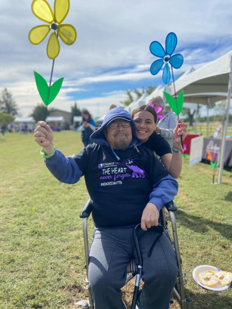 A man in a wheelchair smiling with a caregiver