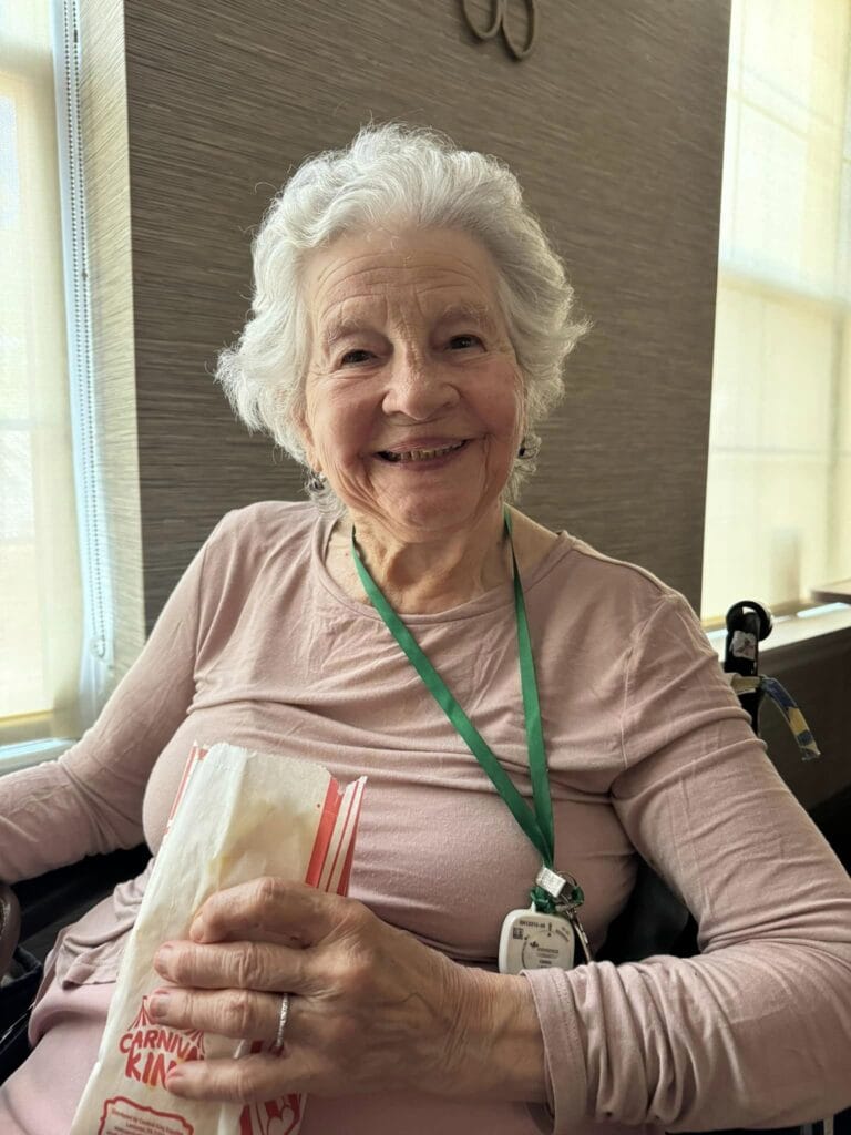 A woman with dementia smiling with a donut in her hand