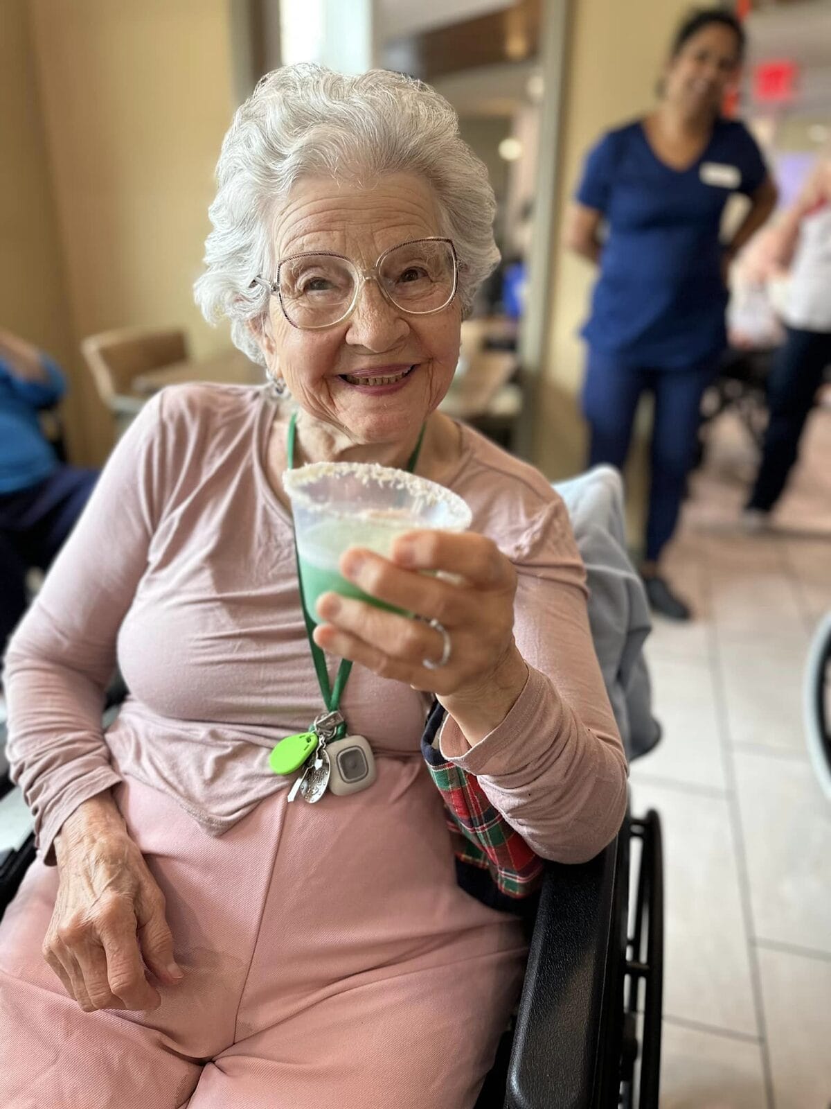 A senior with limited mobility holding a mocktail drinking and smiling