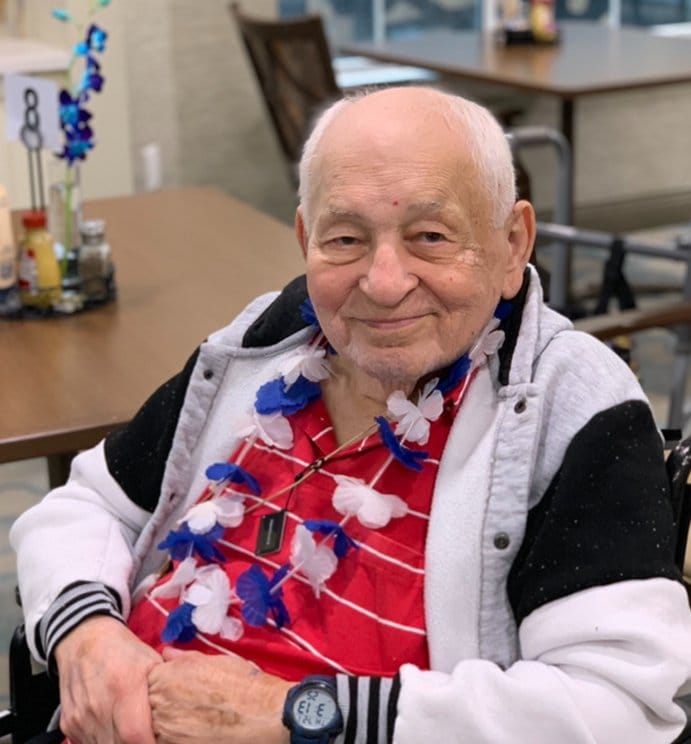 A senior with limited mobility at a restaurant smiling at the camera