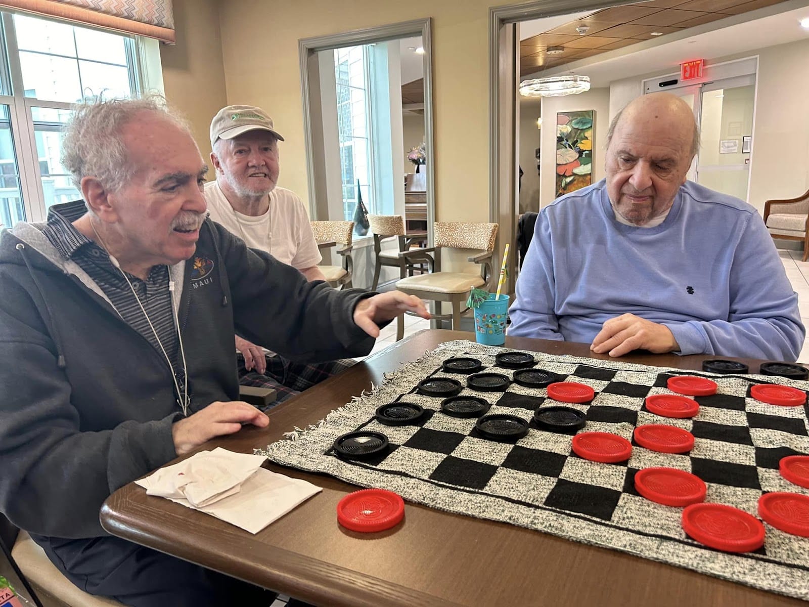 Seniors seated at a table and playing checkers together