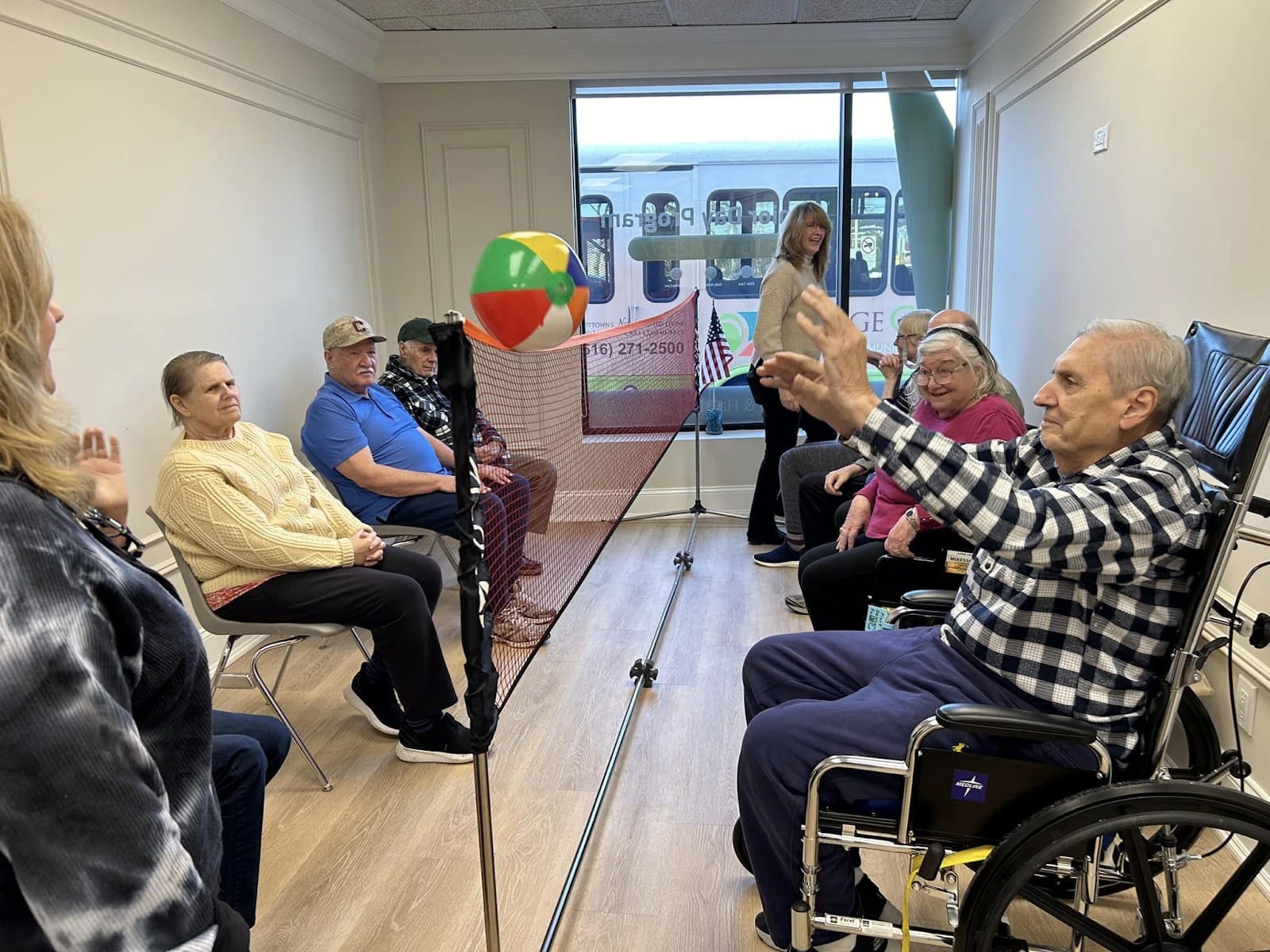 Seniors in wheelchairs playing volleyball with a blow-up beach ball.