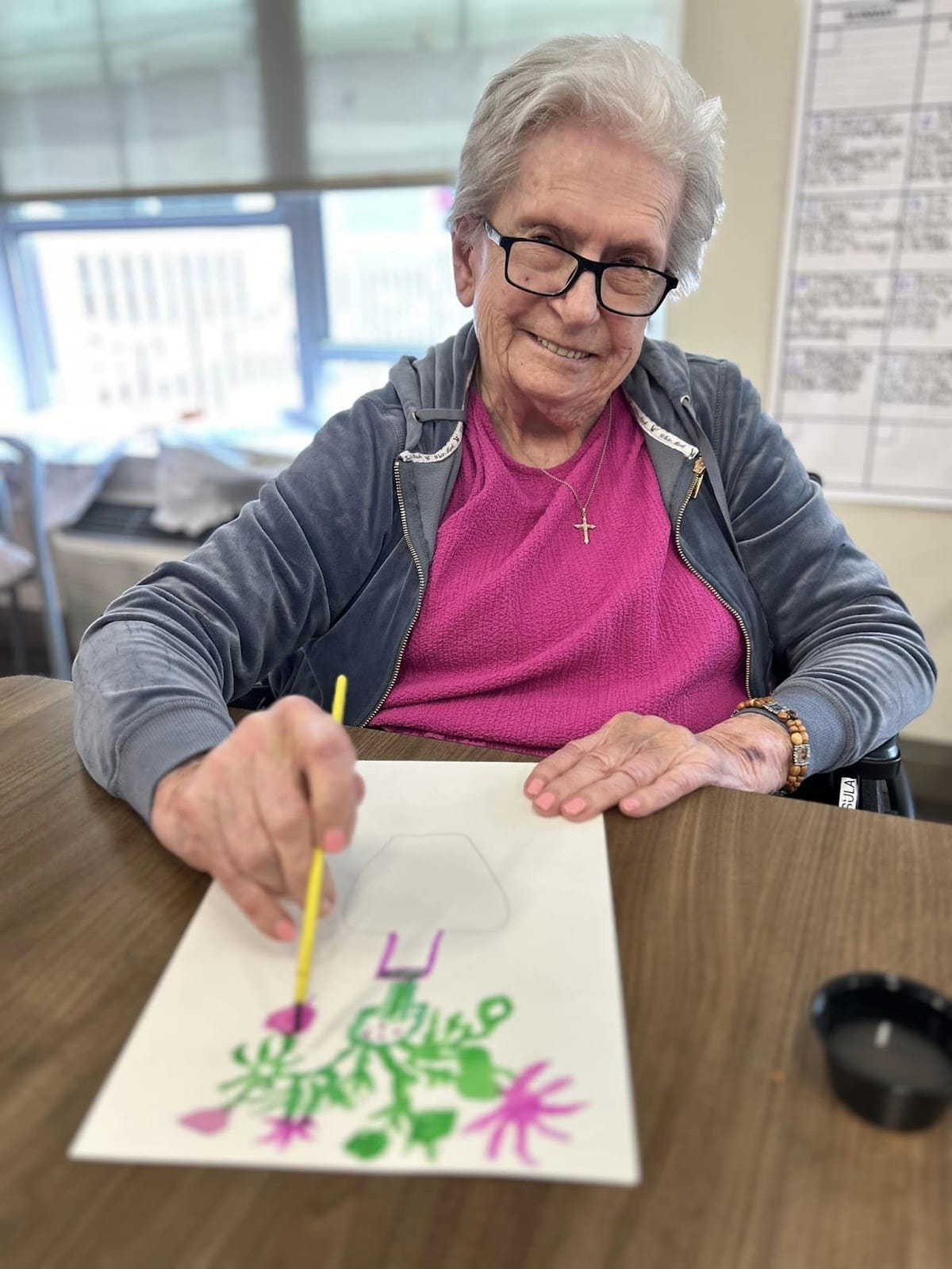 A senior smiling with a drawing they created