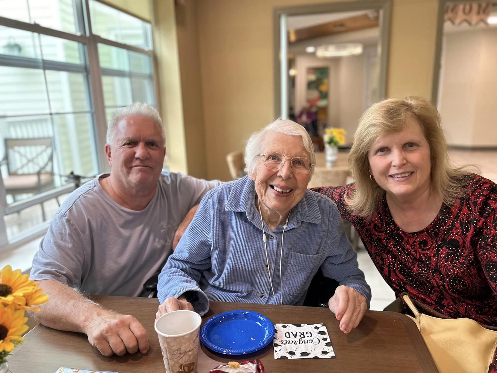 An elderly woman smiling with what appears to be her parents to her left and right