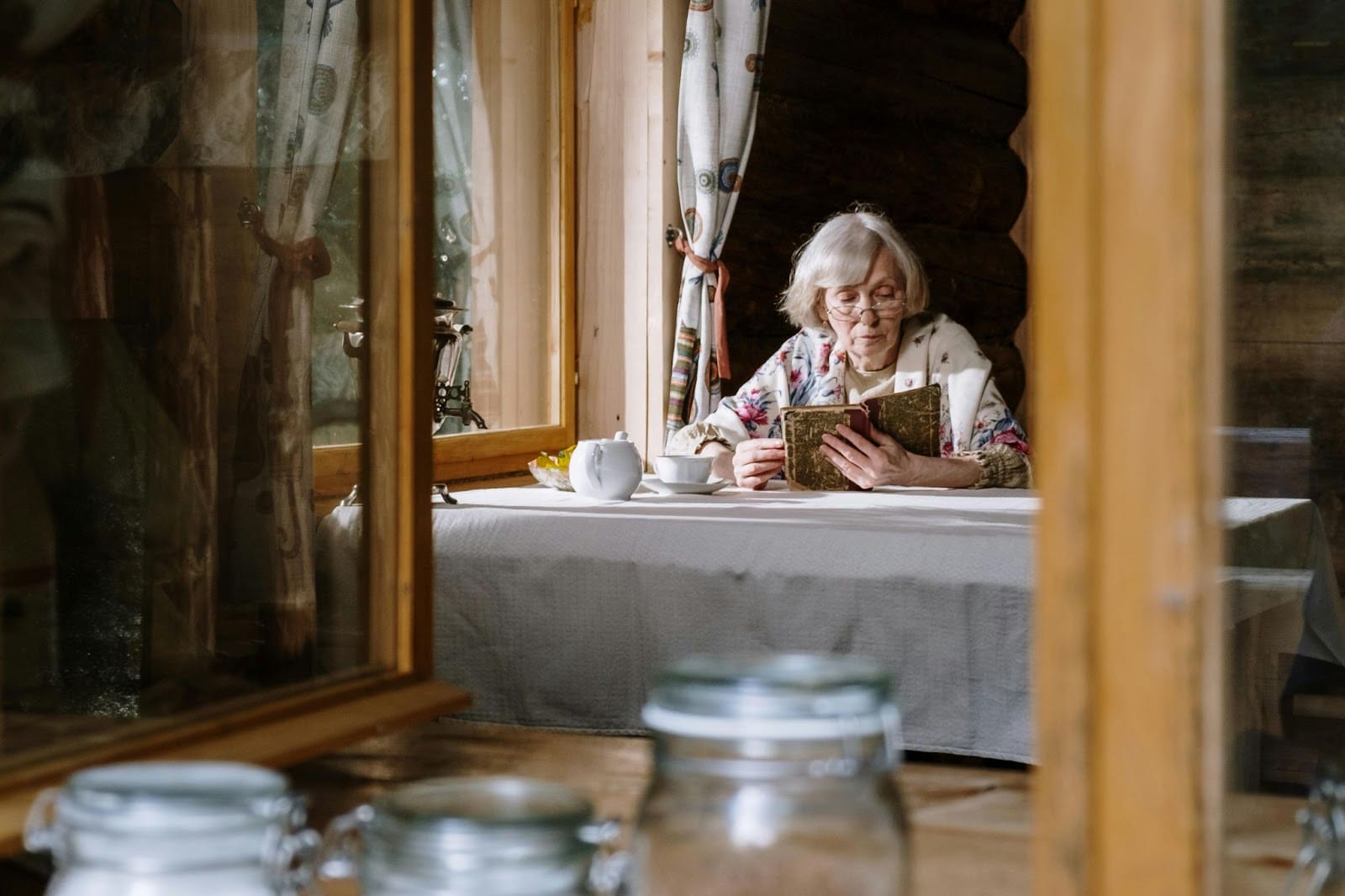 A senior reading a book at a table with tea