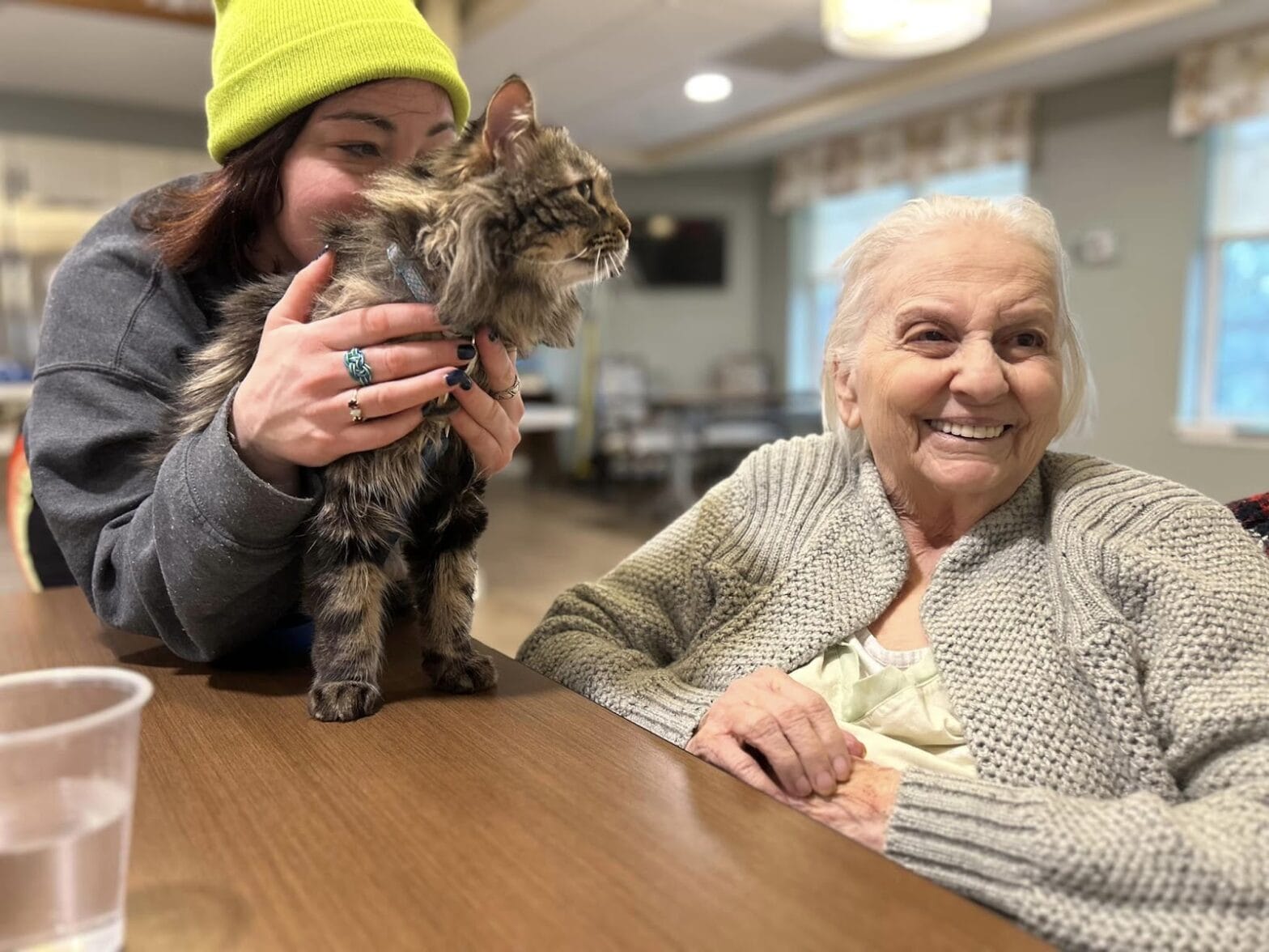 A woman smiling with a cat near by her