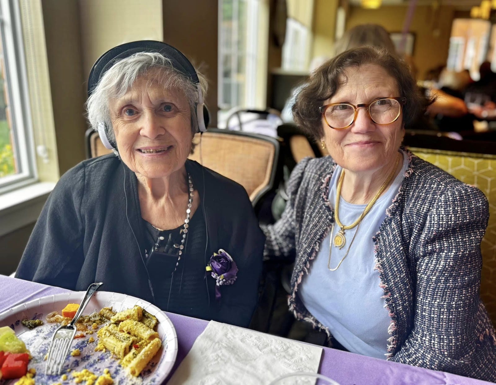 Two women smiling at the camera with food in front of them