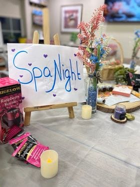 A sign that reads "Spa Night" with candles and tea next to it