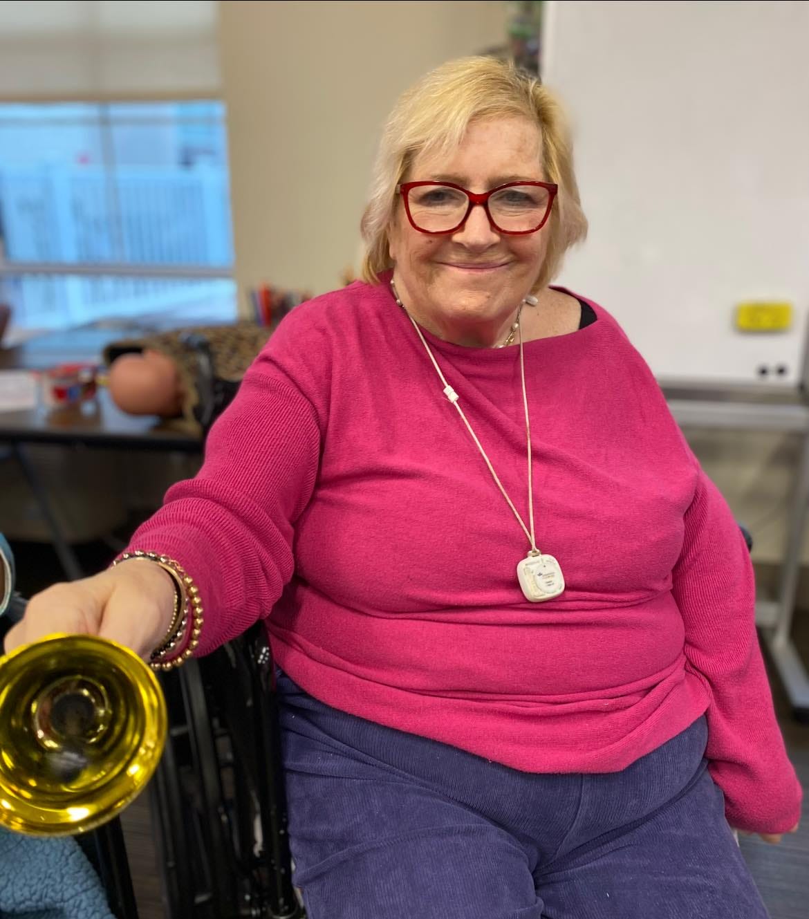 A senior holding a brass horn in a music therapy session