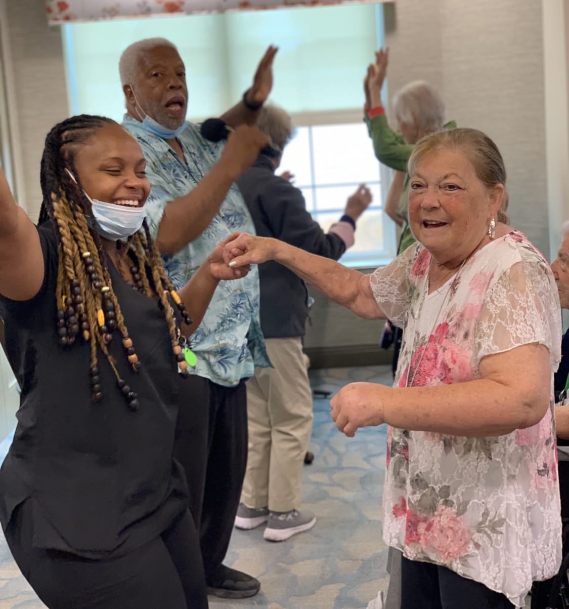 Elderly people dancing with a person in the background singing in a microphone