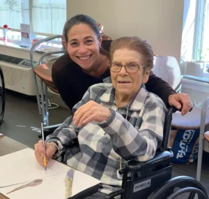 Caregiver assisting senior woman painting
