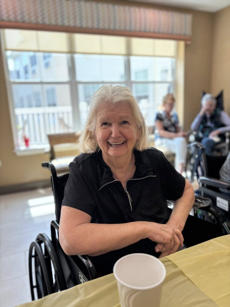 A memory care resident smiling while in a wheelchair