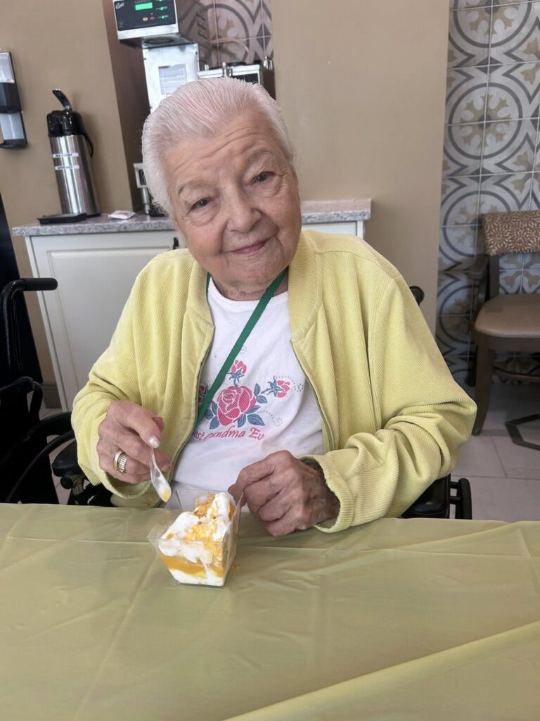 A picture of a senior citizen eating a fruit and yogurt cup