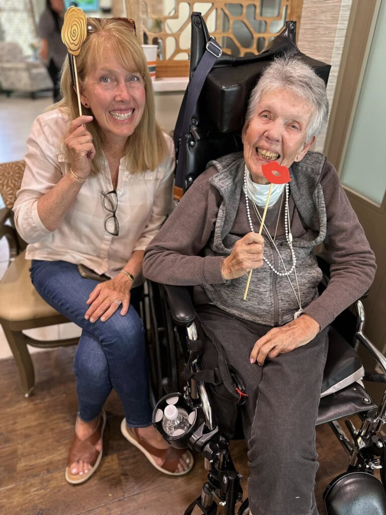 Two woman smiling one in a wheelchair and the other on a seat